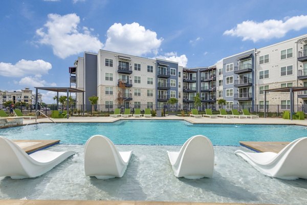 Resort-style pool with lounging areas at The District in Little Elm Apartments