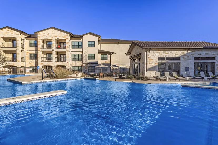 Rooftop swimming pool with lounge chairs at Agora Stone Oak Apartments