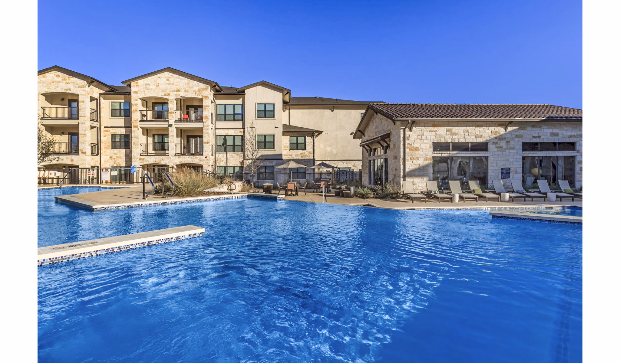 Rooftop swimming pool with lounge chairs at Agora Stone Oak Apartments