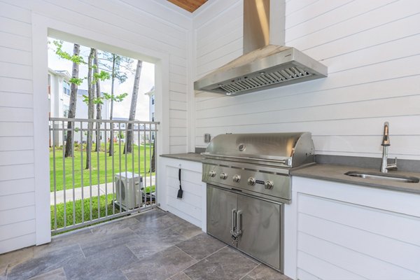 Outdoor grill area with modern seating at Wyldewood Gosling Apartments, ideal for social gatherings and al fresco dining