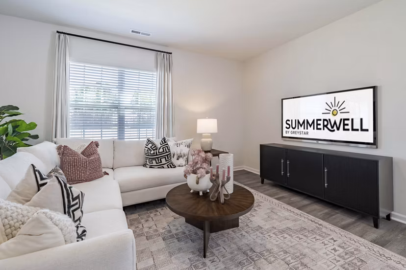 Spacious living room with modern decor in Summerwell Harmony Apartments, featuring comfortable seating and large windows