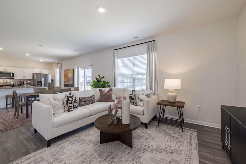 Living room featuring modern decor and large windows at Summerwell Harmony Apartments