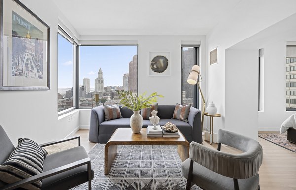 Living room with modern decor and large windows at The Sudbury Apartments