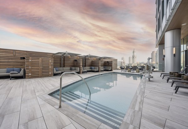 Luxurious outdoor pool at The Sudbury Apartments with loungers and city skyline views