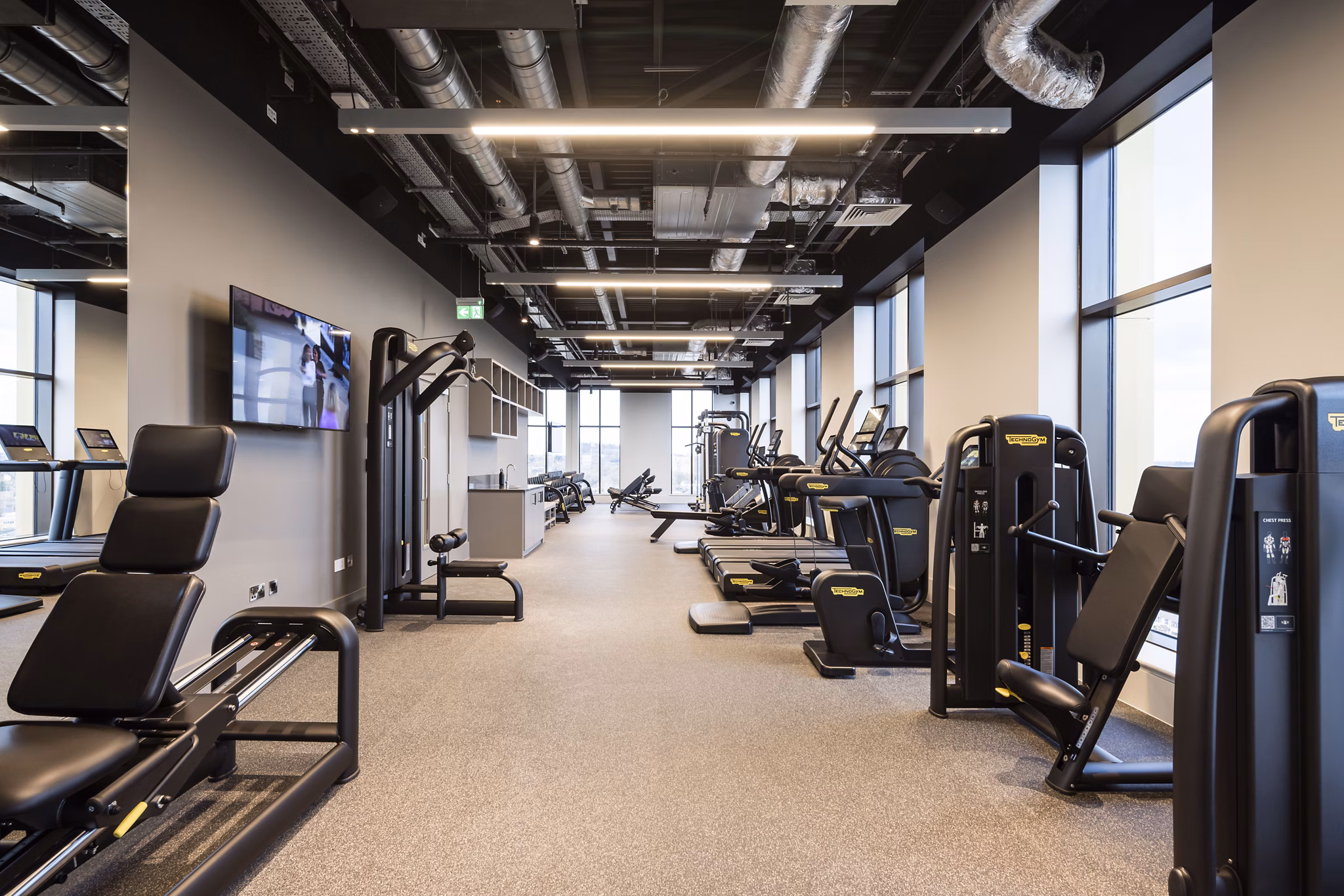 Modern fitness room at Greenford Quay Glassworks with a variety of exercise equipment and large windows for natural light.