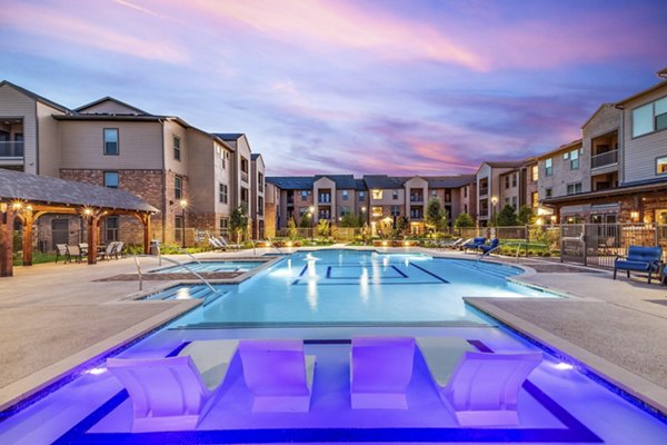 Modern outdoor pool at Alders Cross Creek Apartments with serene views and lounge seating, perfect for relaxation and leisure activities