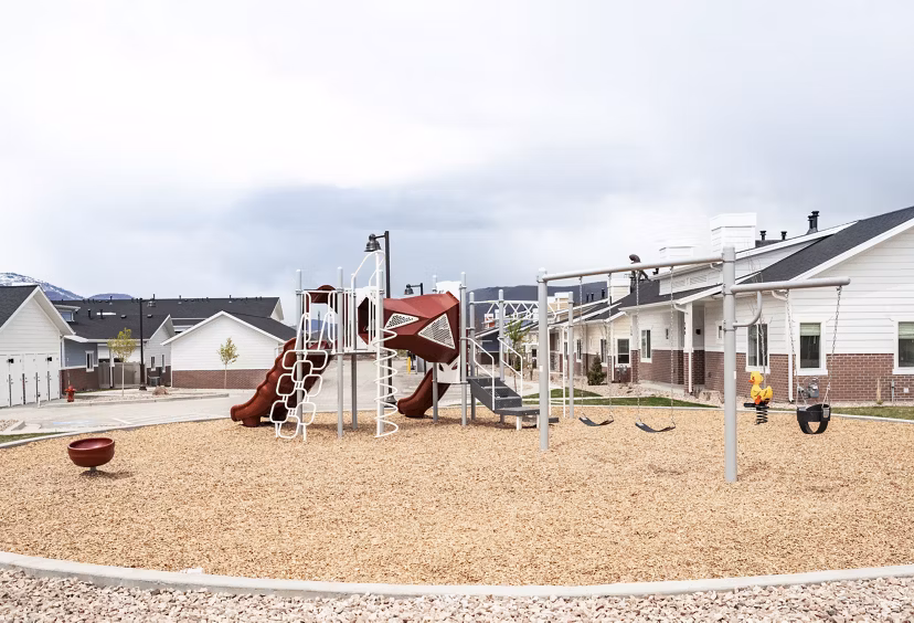 Children's playground at Milano Apartments, featuring colorful play structures and green spaces