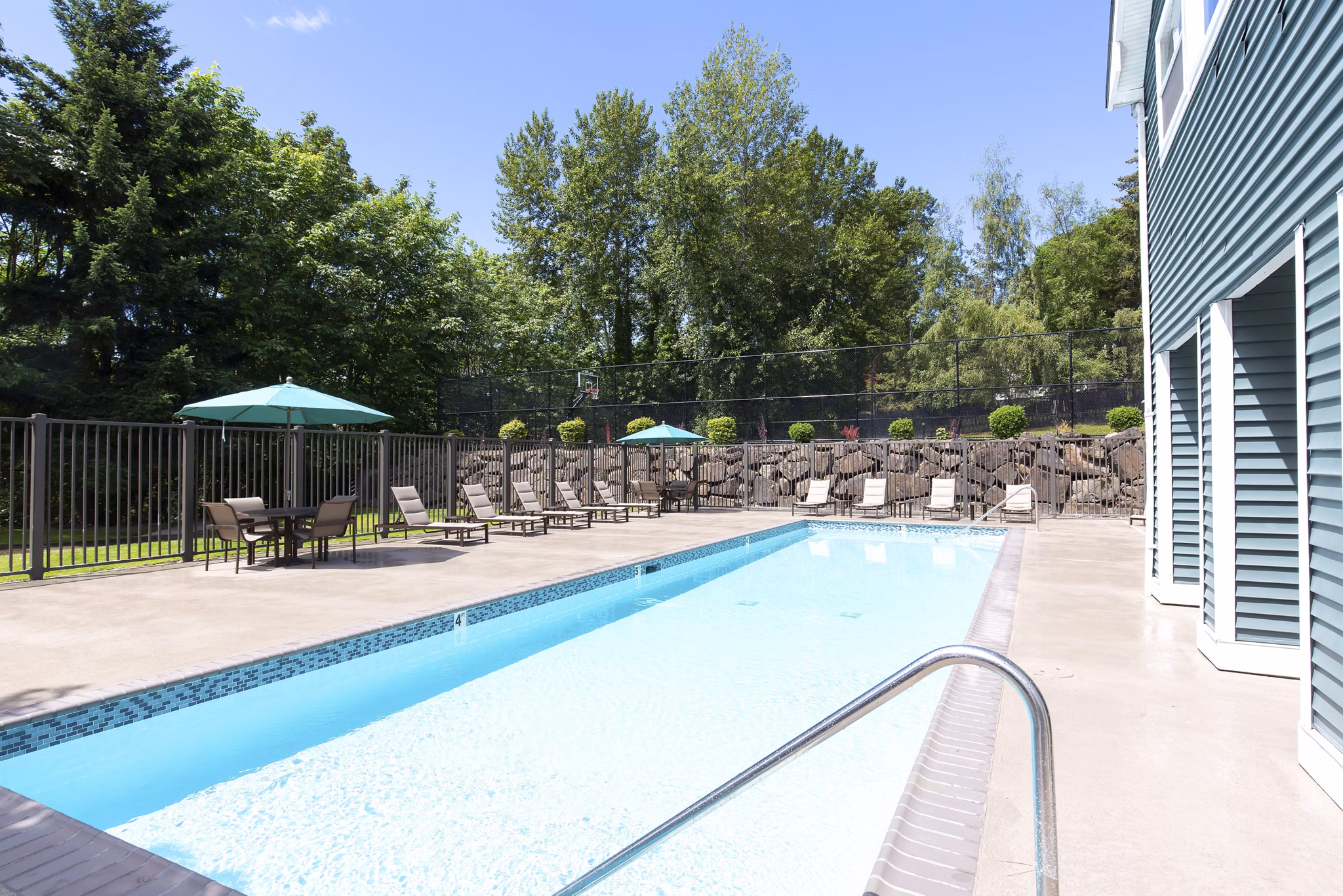 Luxurious pool area with lounge chairs at Alaire Apartment Homes, offering relaxation and scenic views in a modern setting