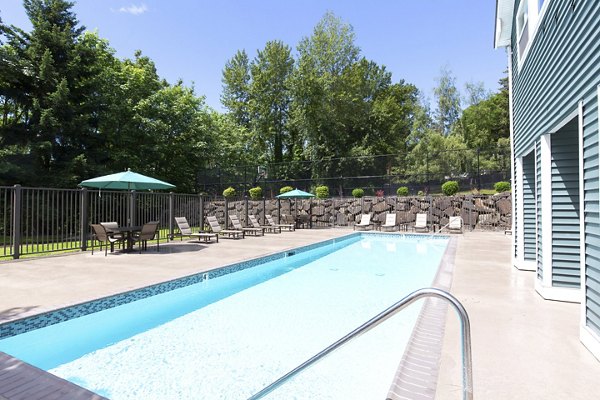 Luxurious pool area with lounge chairs at Alaire Apartment Homes, offering relaxation and scenic views in a modern setting