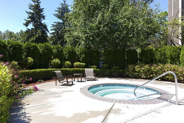 Poolside relaxation area at Alaire Apartment Homes featuring resort-style pool and lush landscaping