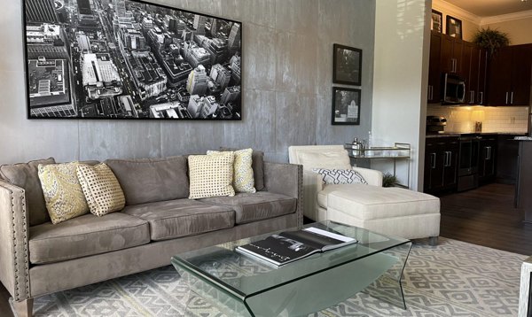 Living room with modern decor and large windows at Ardmore & 28th Apartments