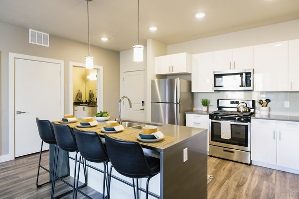 Modern kitchen with stainless steel appliances and granite countertops in Milagro Apartments