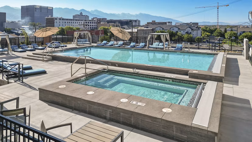 Luxurious outdoor pool with lounge seating at Milagro Apartments