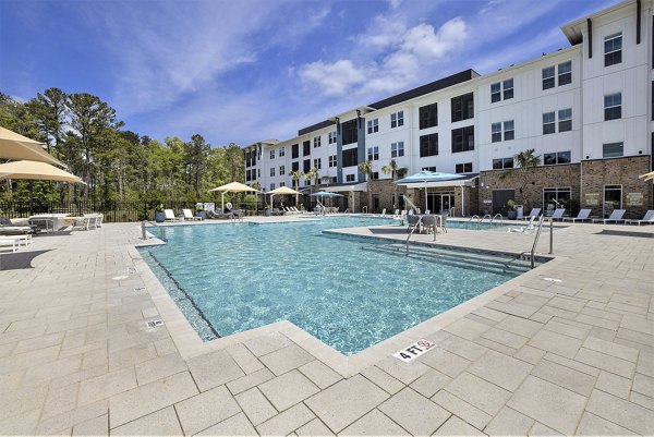 Resort-style pool surrounded by lush landscaping at Satori West Ashley Apartments, luxury community living in Charleston