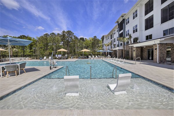 Poolside relaxation and tranquil views at Satori West Ashley Apartments' luxury pool