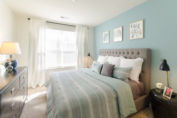 Cozy bedroom featuring stylish decor and large window at The Victor Stonebridge Apartments