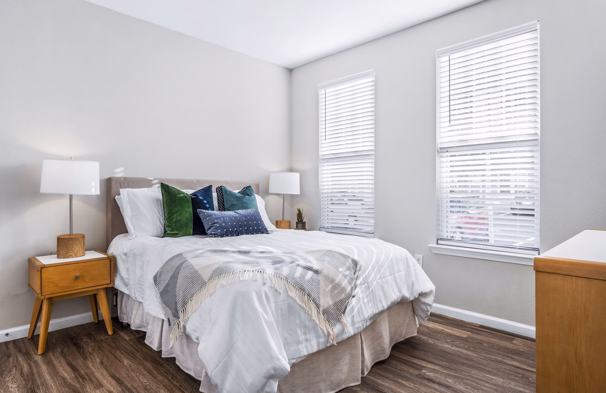 Cozy bedroom with modern decor in Jefferson at Dedham Station Apartments, featuring ample natural light and stylish furnishings