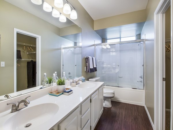 Modern bathroom featuring a double sink vanity and glass shower door at luxury apartments