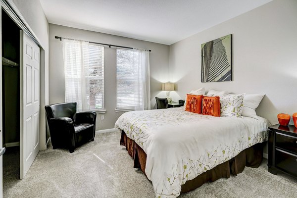 Bedroom featuring plush bedding and large windows at Creekside at Highlands Ranch Apartments, offering luxury living in a serene setting