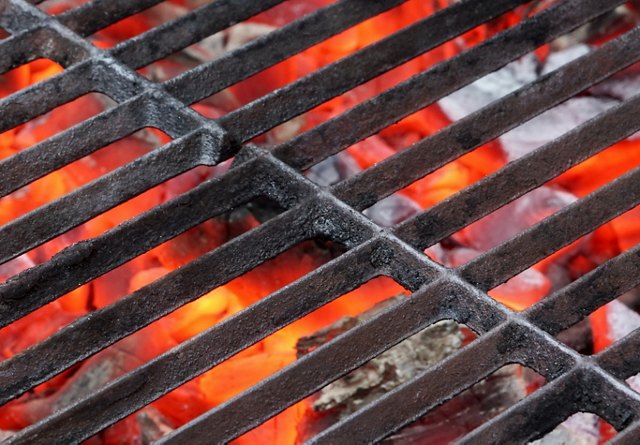 Close-up of a hot barbecue grill with glowing red coals underneath.