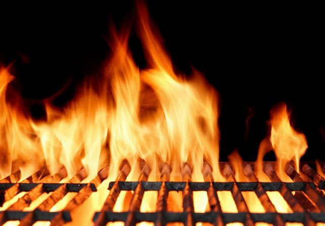 Intense flames rising from a hot barbecue grill.