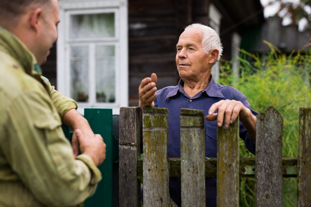 European senior man having conversation with his neighbour outdoors.
