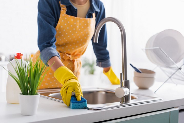 Cropped view of housewife with sponge cleaning sink in kitchen