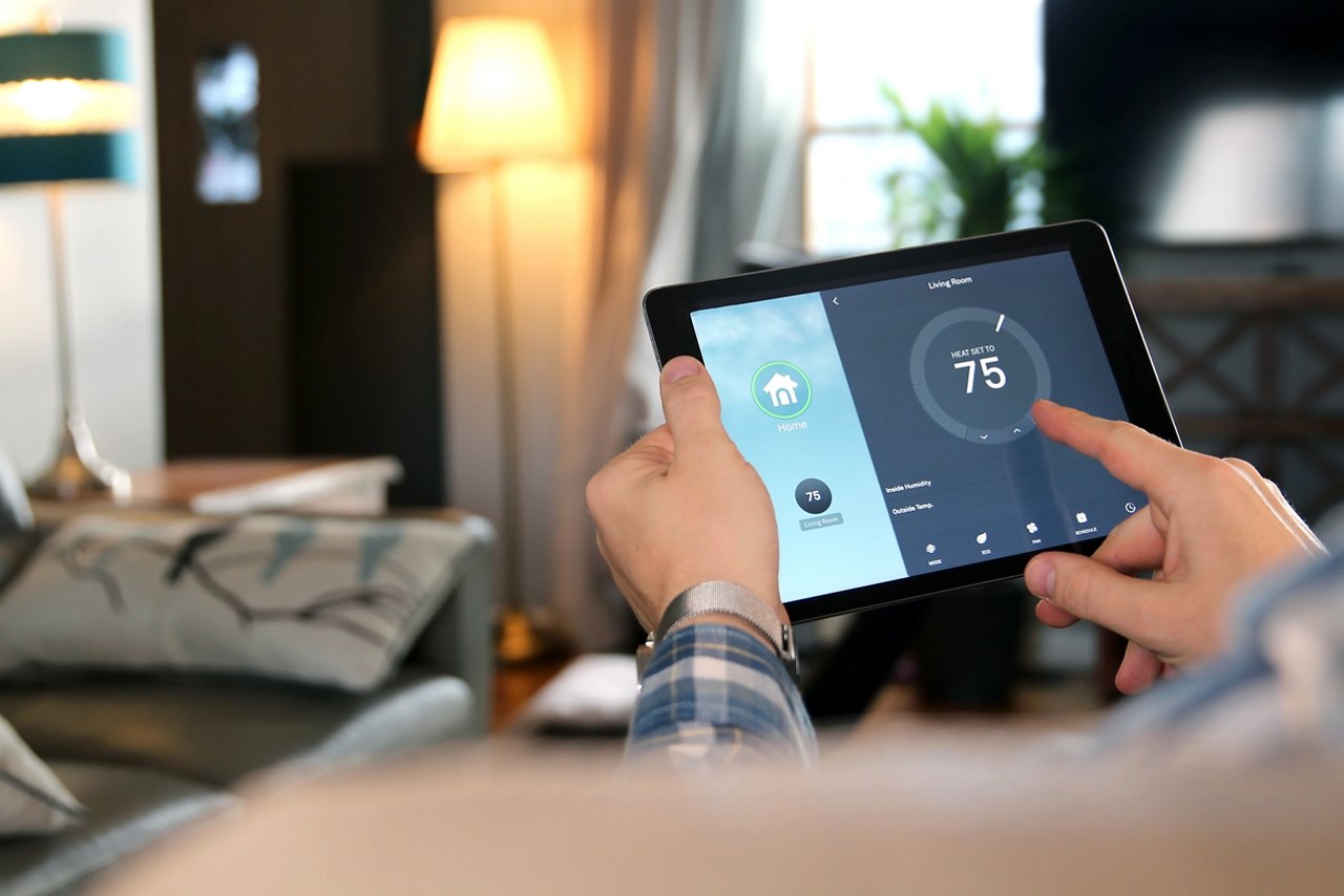 Man is Adjusting a  temperature using a tablet with smart home app in modern living room