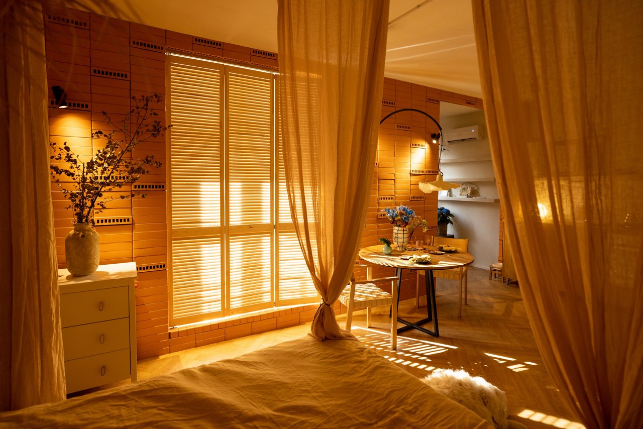 Sunny and cozy studio apartment with the sun's rays passing by the shutters. Interior made in warm tones with natural materials
