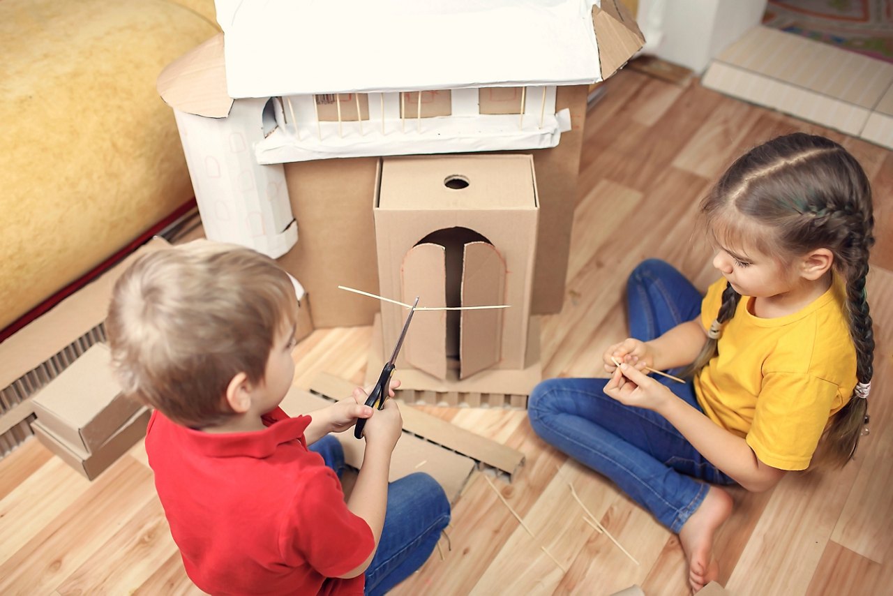 Zero waste home activity. Kids doing paper house with cardboard box after online delivery and playing together, creative idea for home isolation. Imagination skills and creatively thinking concept