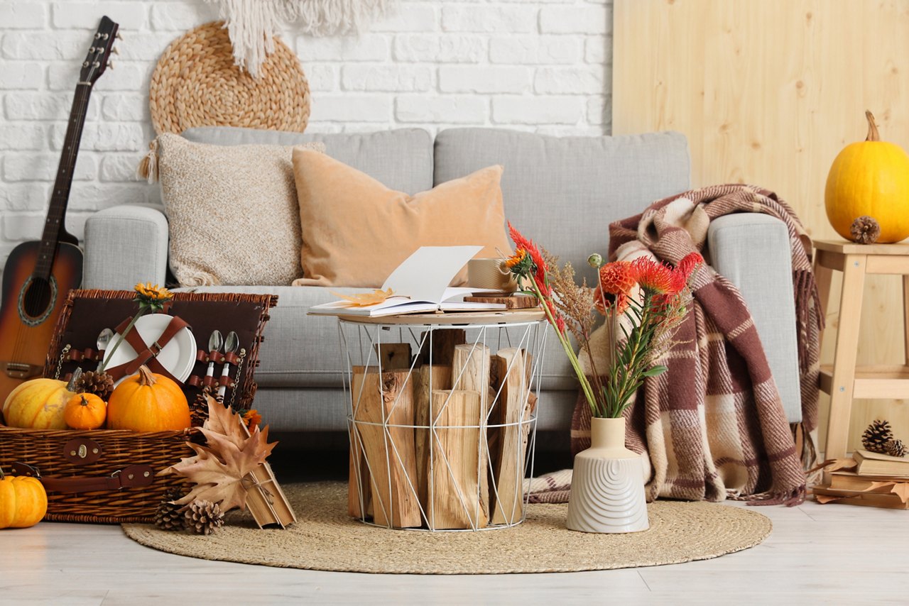 Interior of living room with sofa, picnic basket and autumn decor