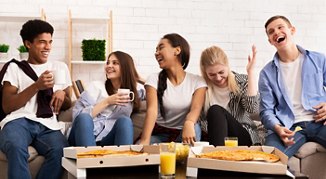 Happy teens eating pizza at home party, talking and laughing, panorama