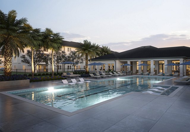 Twilight view of a serene residential pool area surrounded by palm trees, with lounge chairs and umbrellas, reflecting the calm evening sky.