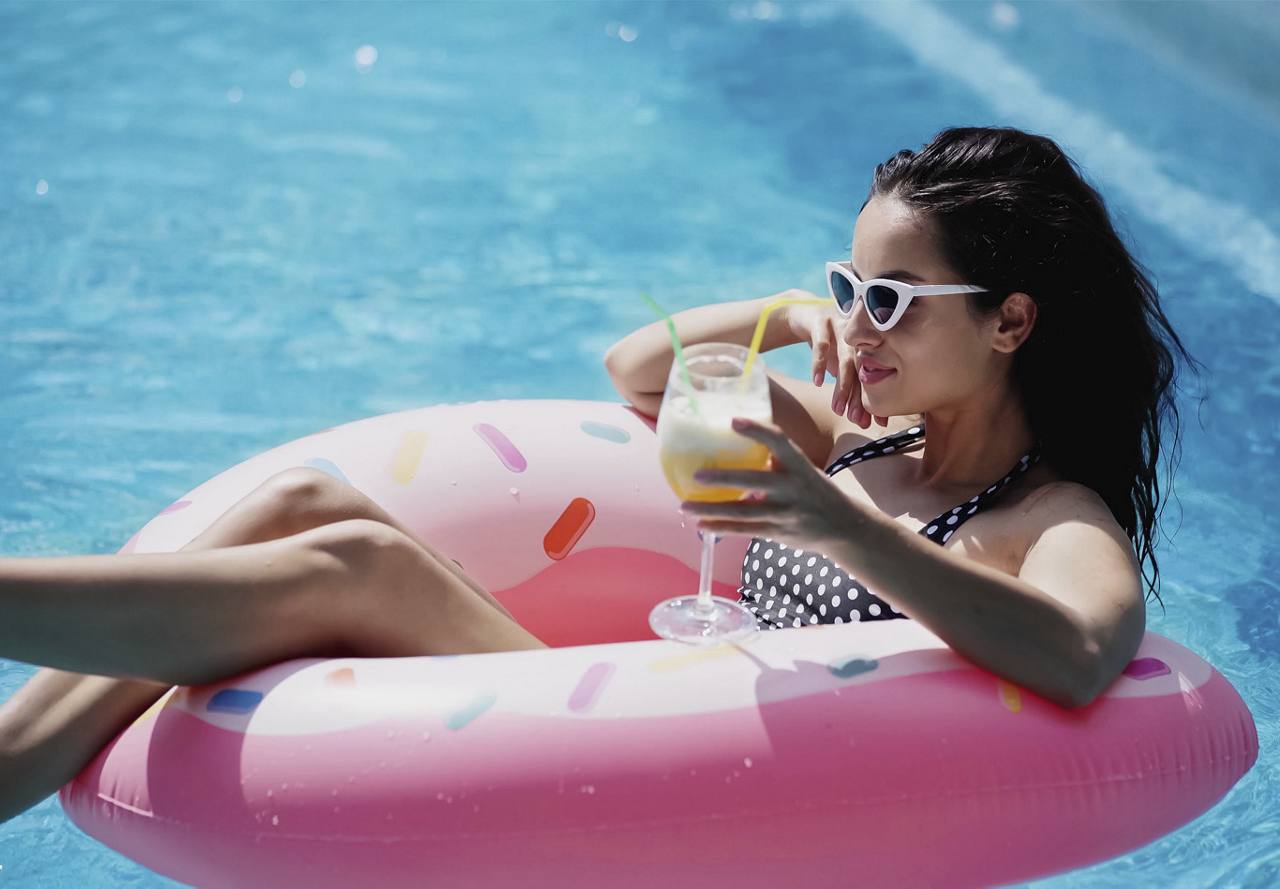 A woman relaxing on a pool float with a drink.