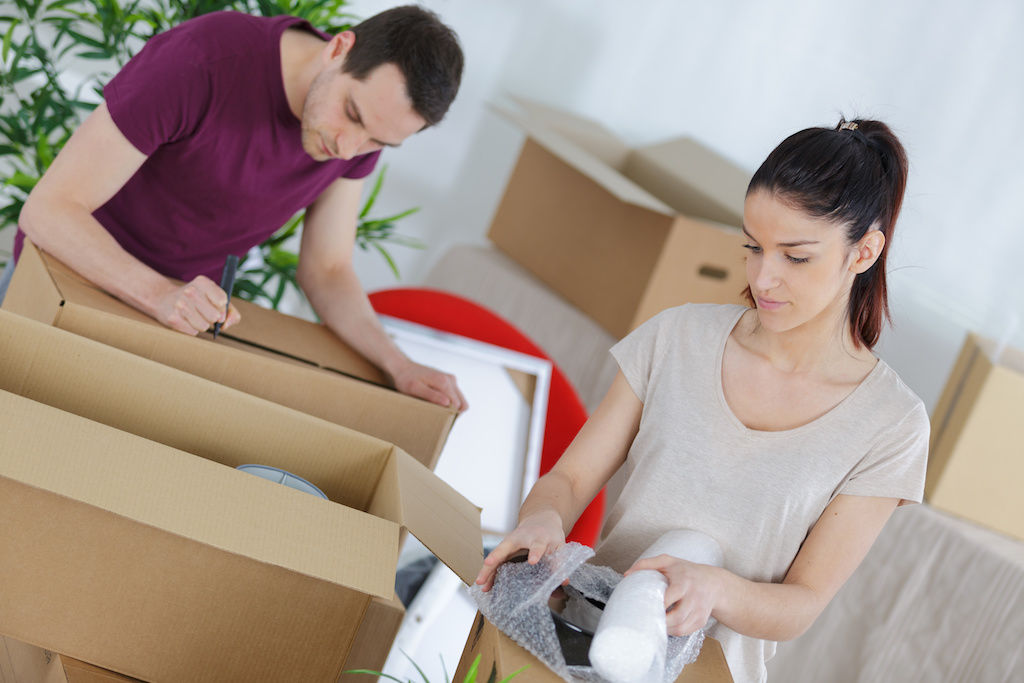 Couple unpacking moving boxes at apartment