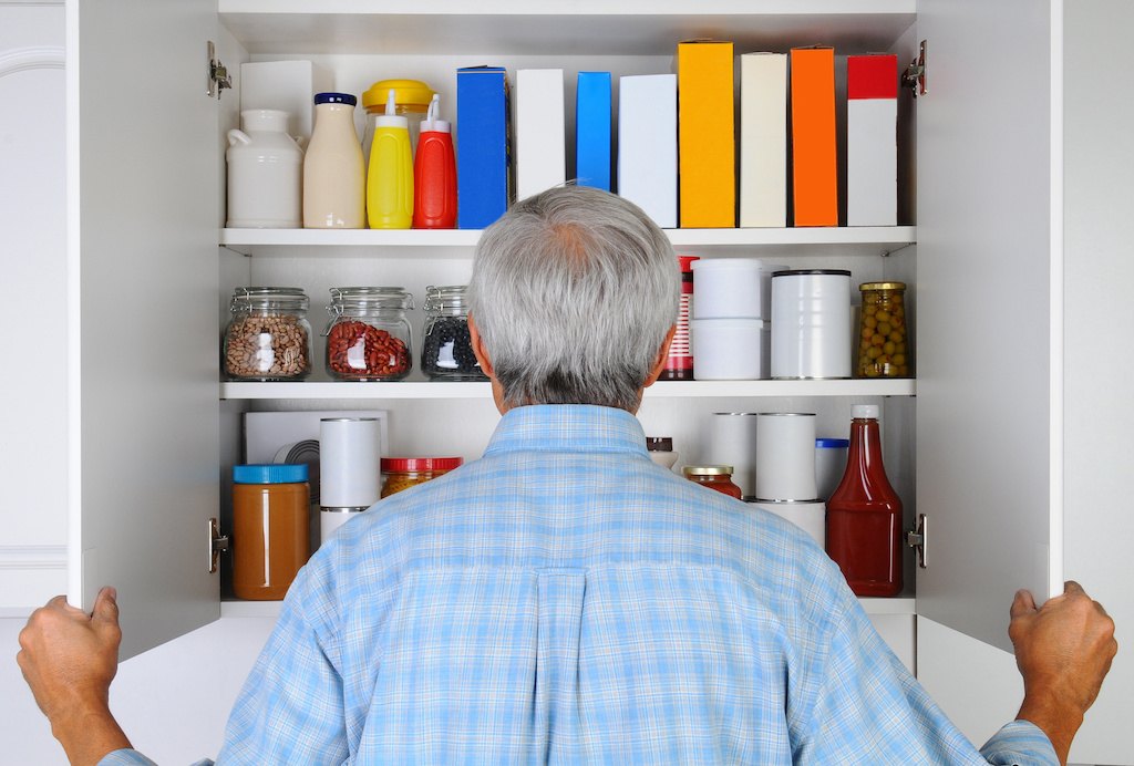 Man looking at canned foods in pantry