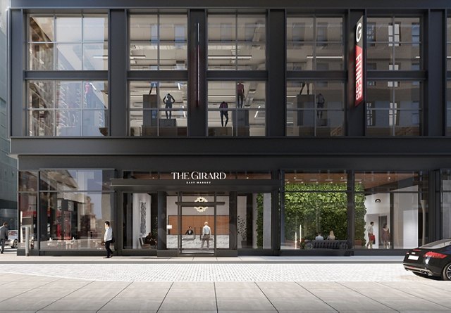 Exterior view of The Girard East Market building with a fitness center on the upper floors and people walking by.