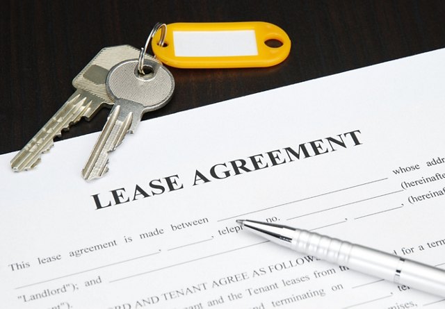 A set of keys on a lease agreement document with a pen, indicating a new rental or lease signing.