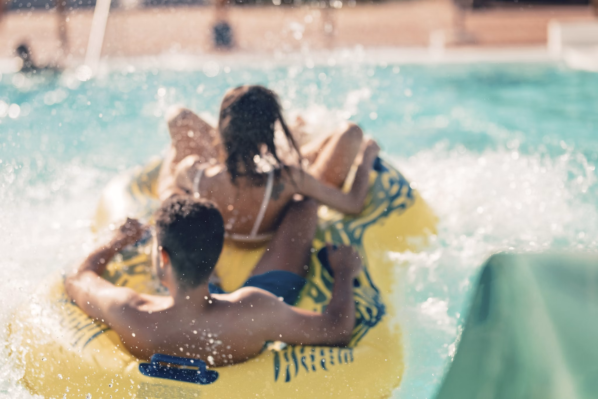Cool people having fun on the water slide with friends and familiy in the aqua fun park glides playing happy and water splashes are all over. Blue sky background looks amazing sunlight