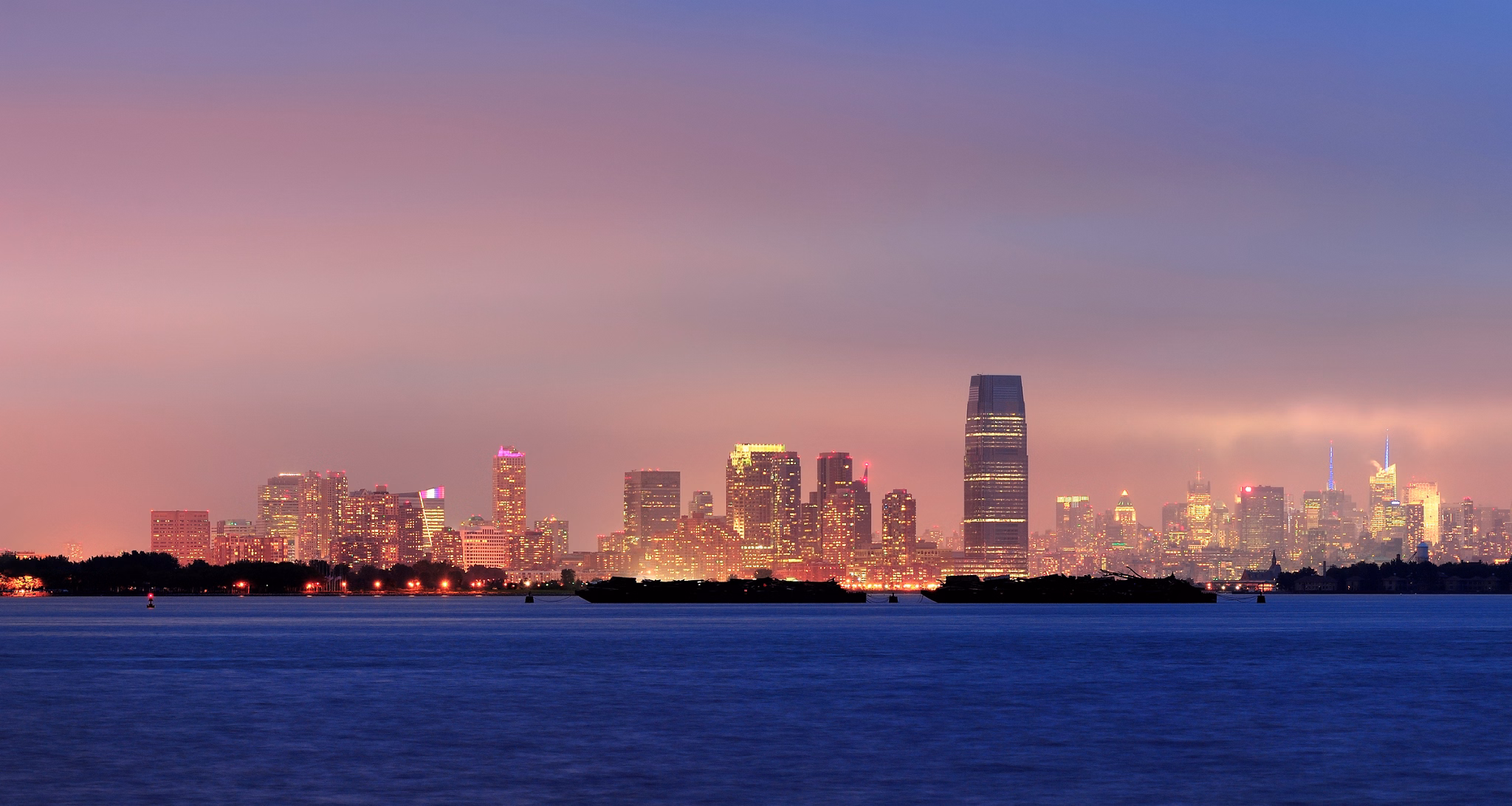 New Jersey skyline at night with skyscrapers over Hudson River.