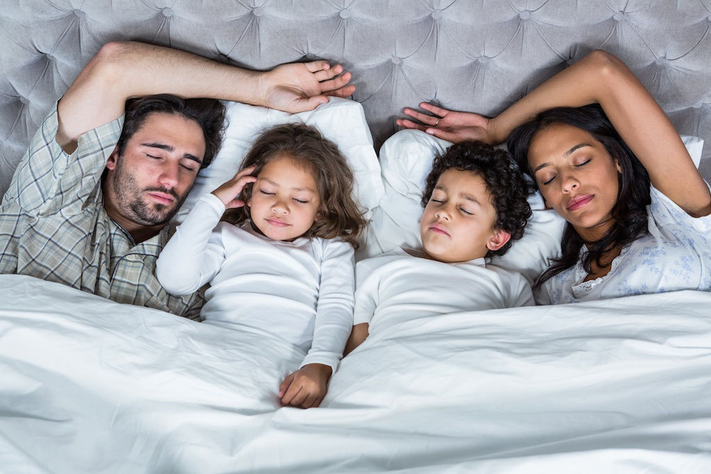 Family of four sleeping in bed at apartment