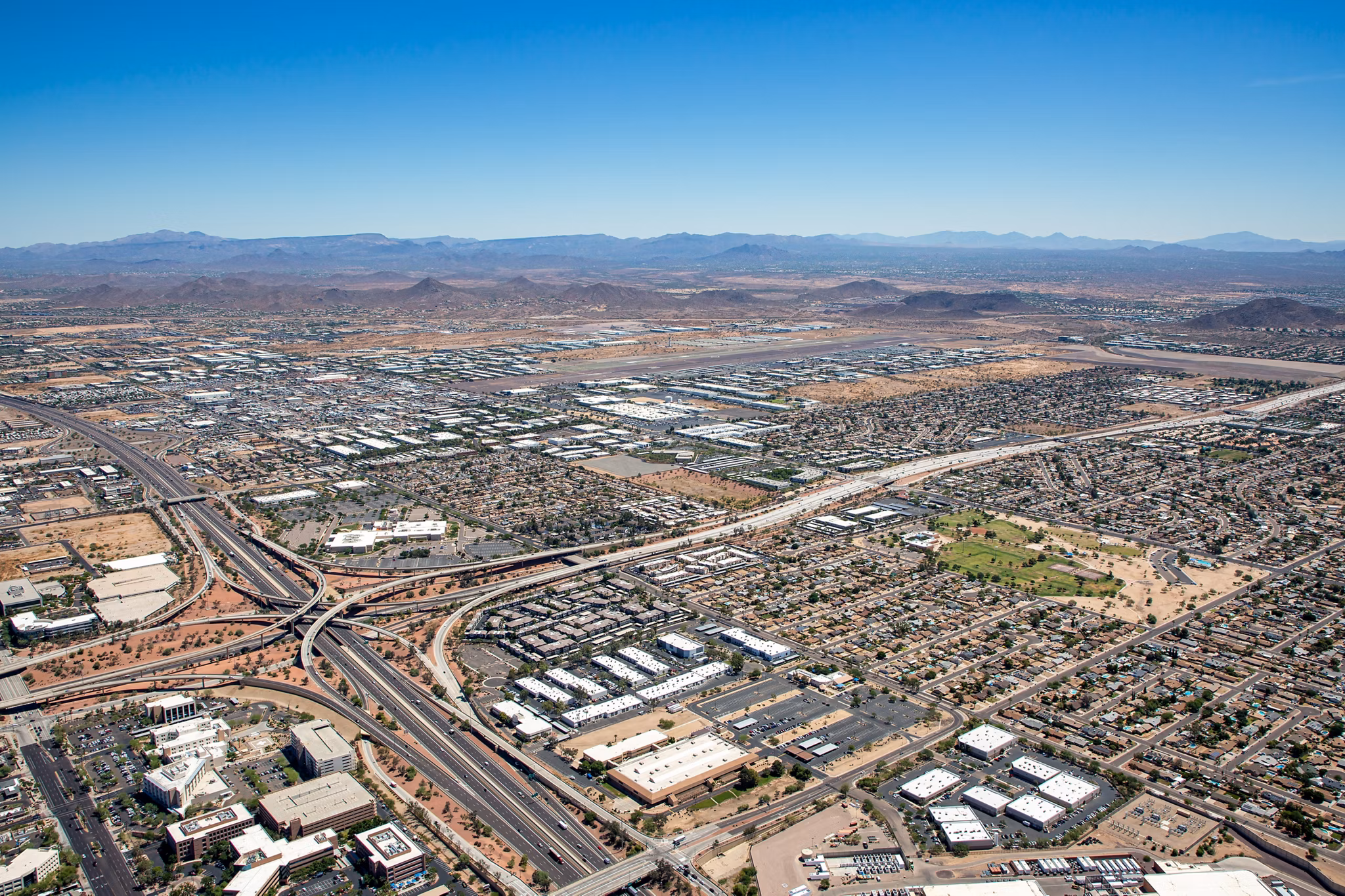 Deer Valley Arizona aerial view showing highway interchange, residential neighborhoods and mountain backdrop - North Phoenix AZ suburb