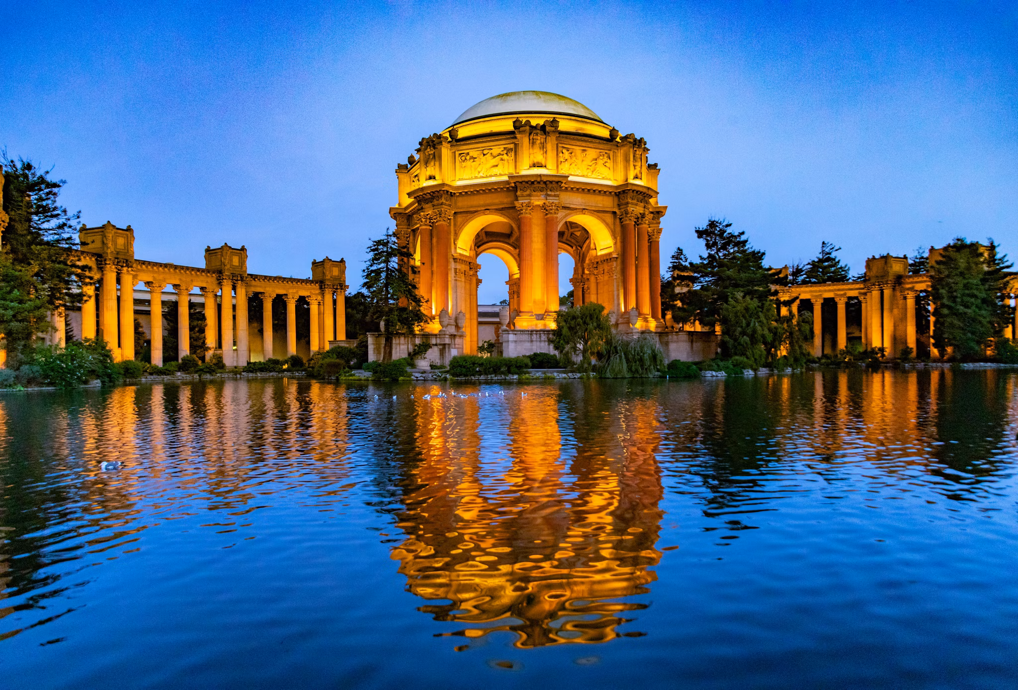  Palace of Fine Arts in San Francisco&apos;s Marina District, California, lit up at dusk with its dome reflected in the lagoon.