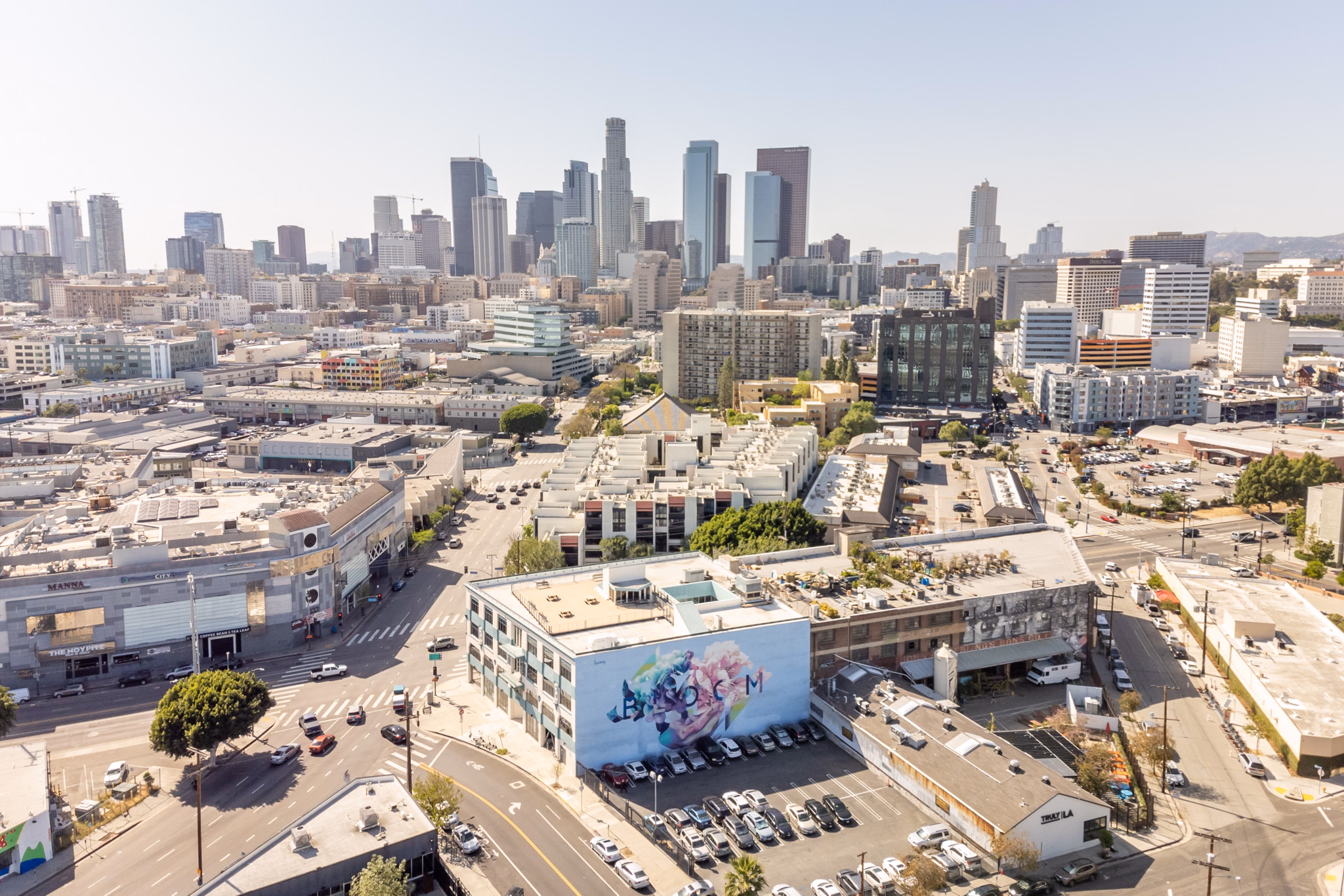 Aerial view of Little Tokyo, California, showcasing urban streets, colorful murals, and the Los Angeles skyline in the background.