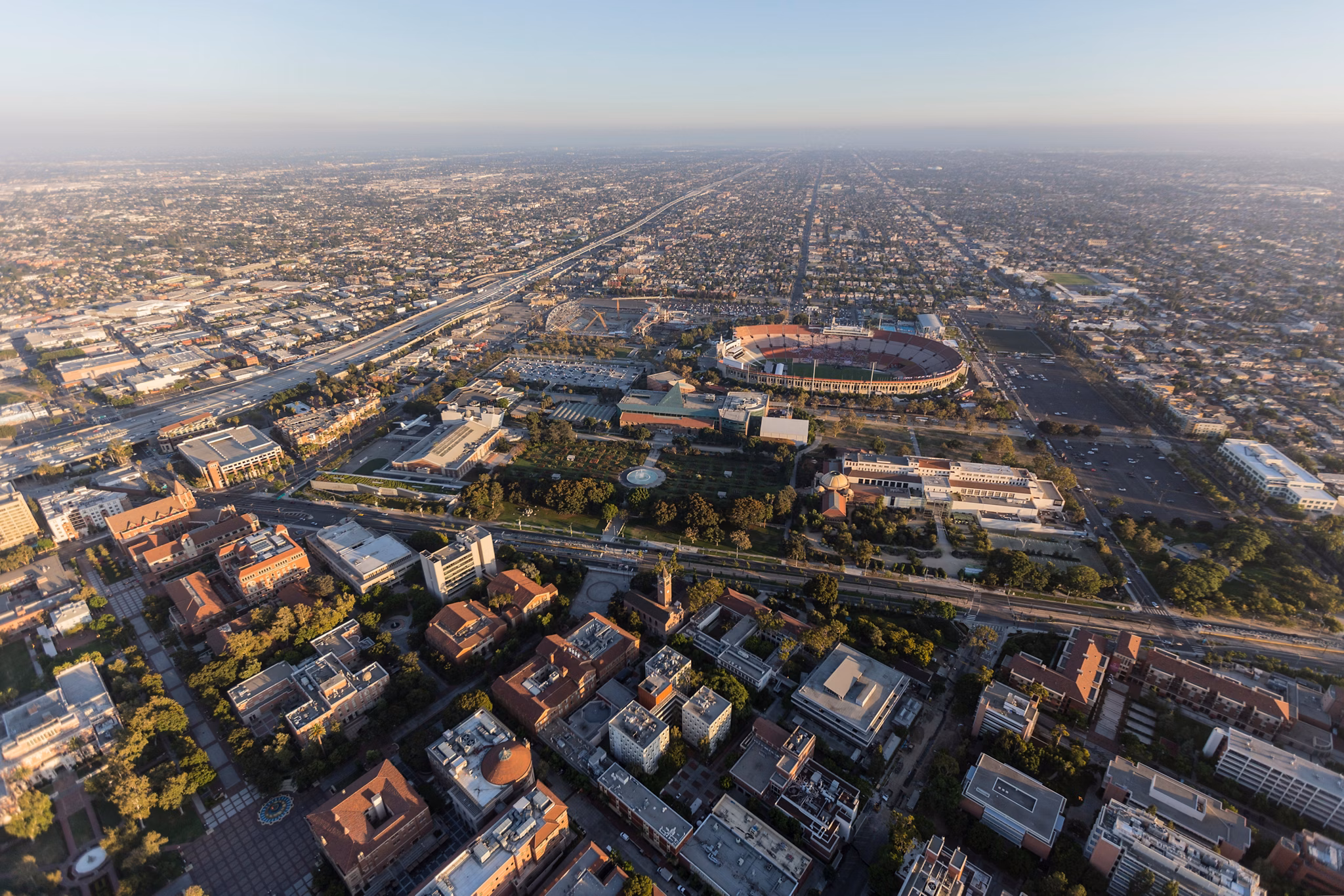 Aerial view of University Park, California, featuring a stadium surrounded by city buildings and roads stretching into the horizon.