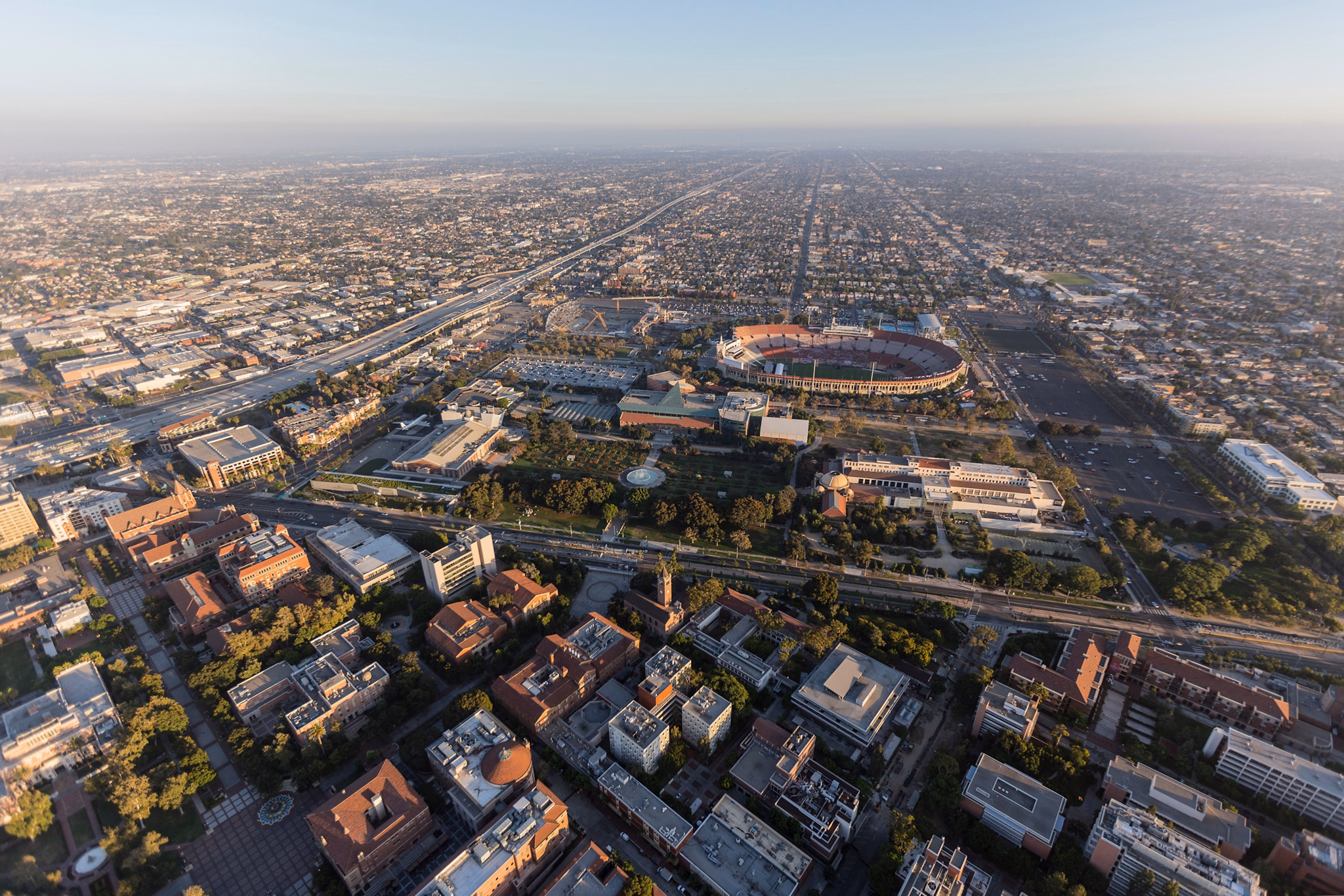 Aerial view of University Park, California, featuring a stadium surrounded by city buildings and roads stretching into the horizon.