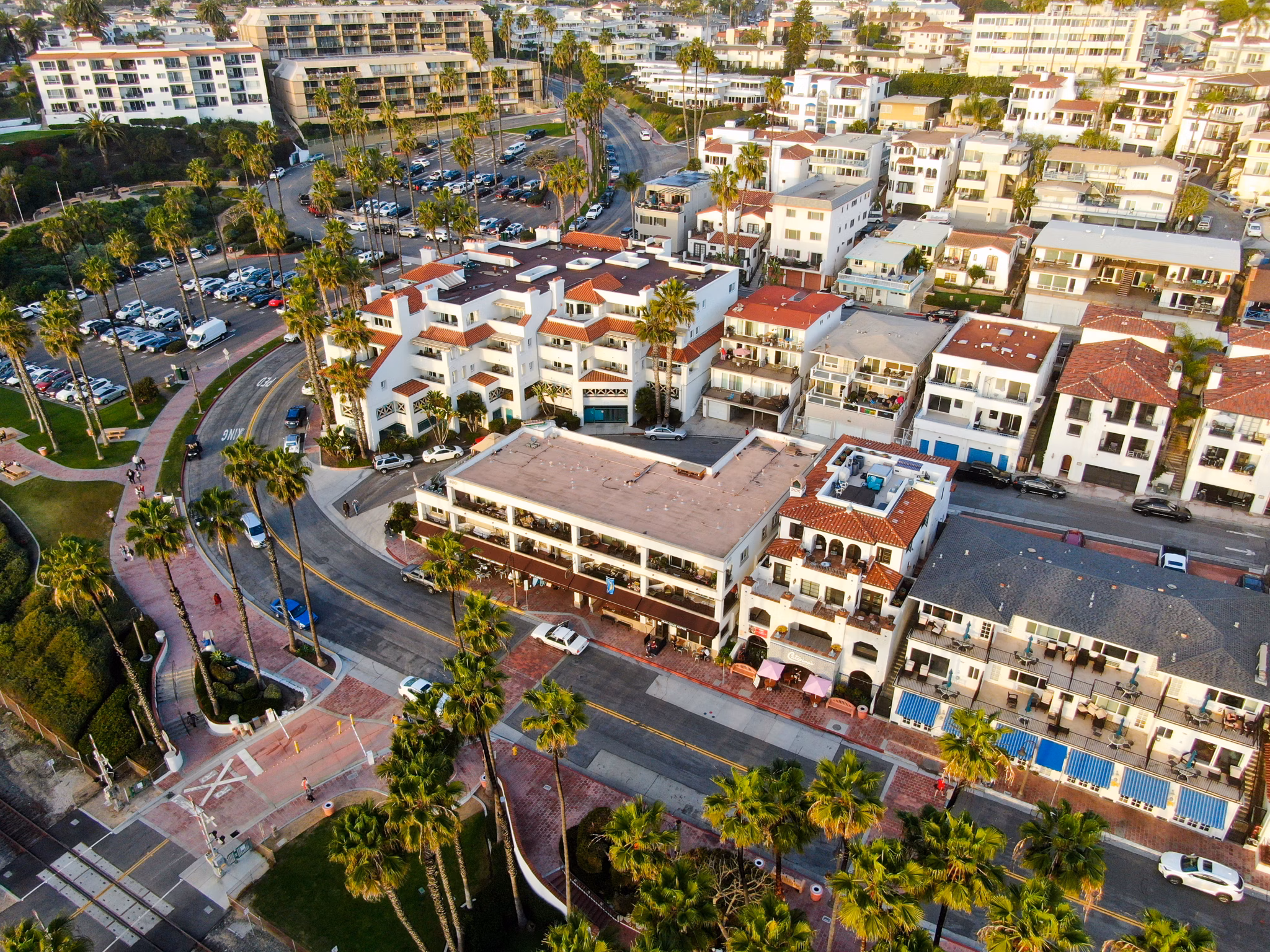 Aerial view of San Clemente, California, featuring white stucco buildings with red roofs, palm-lined streets, and coastal charm.