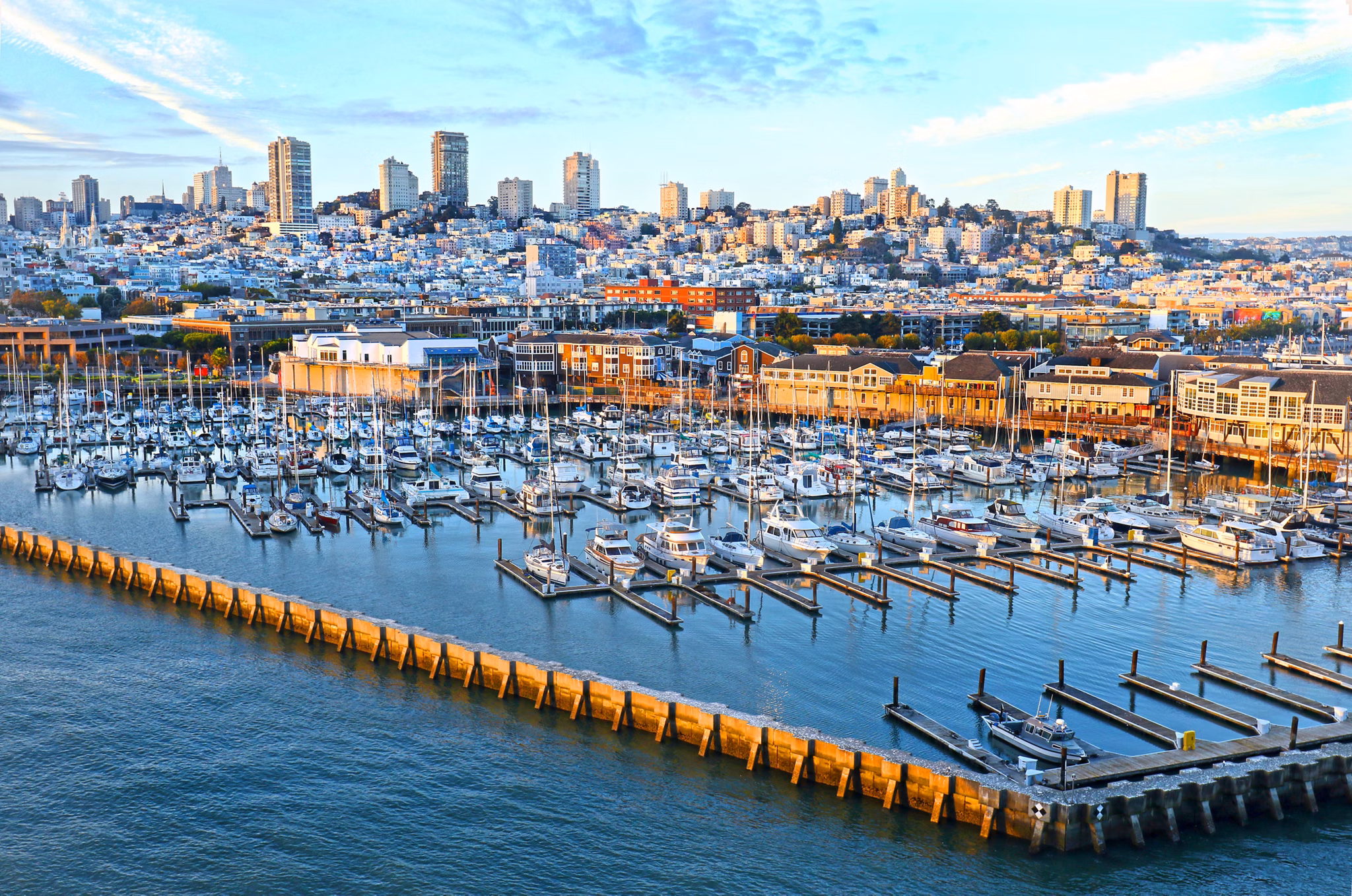 A vibrant marina filled with boats in the North Waterfront neighborhood, California, framed by colorful buildings and city views.