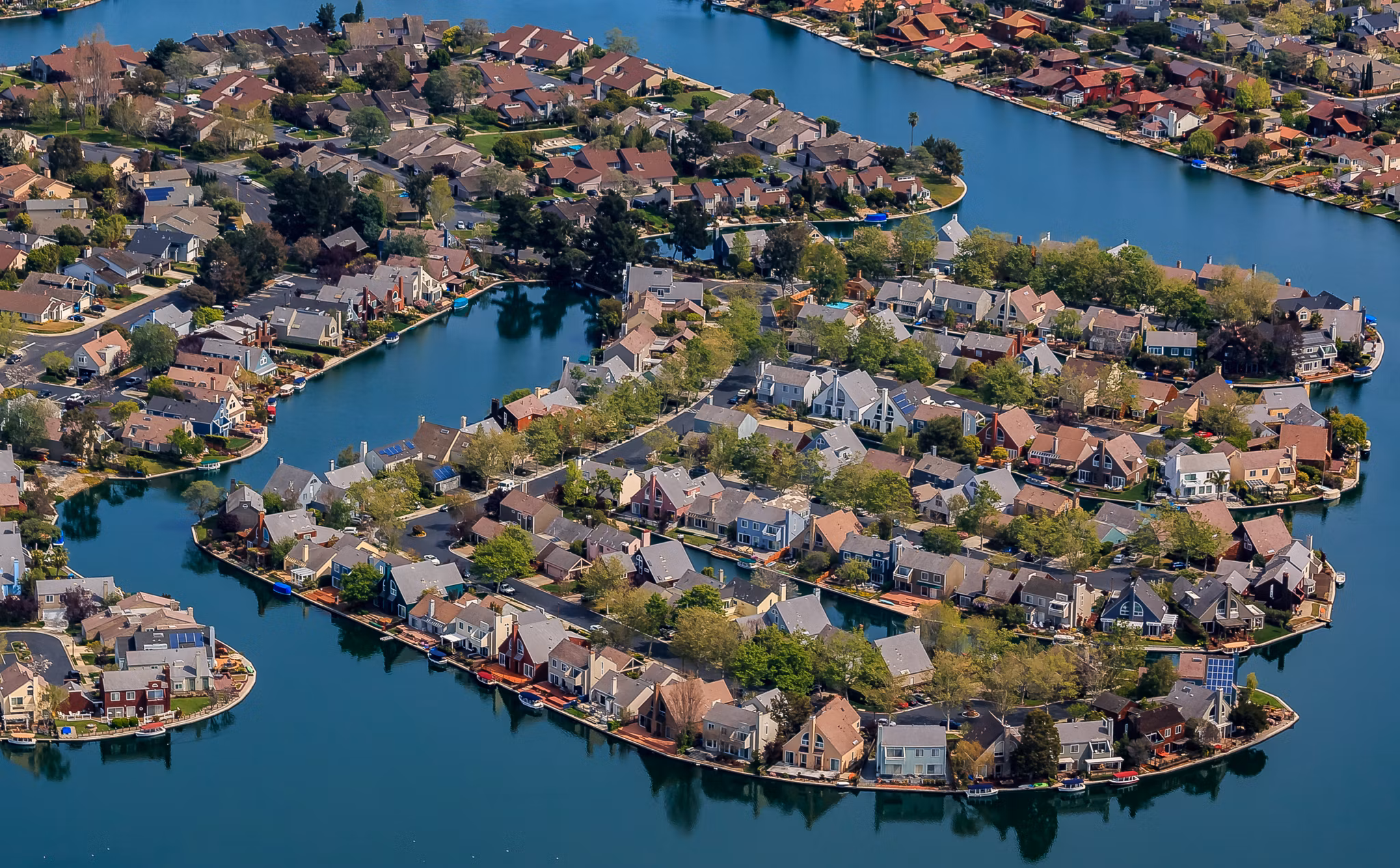 Aerial view of the San Mateo, California neighborhood with houses surrounded by blue waterways and lush greenery.