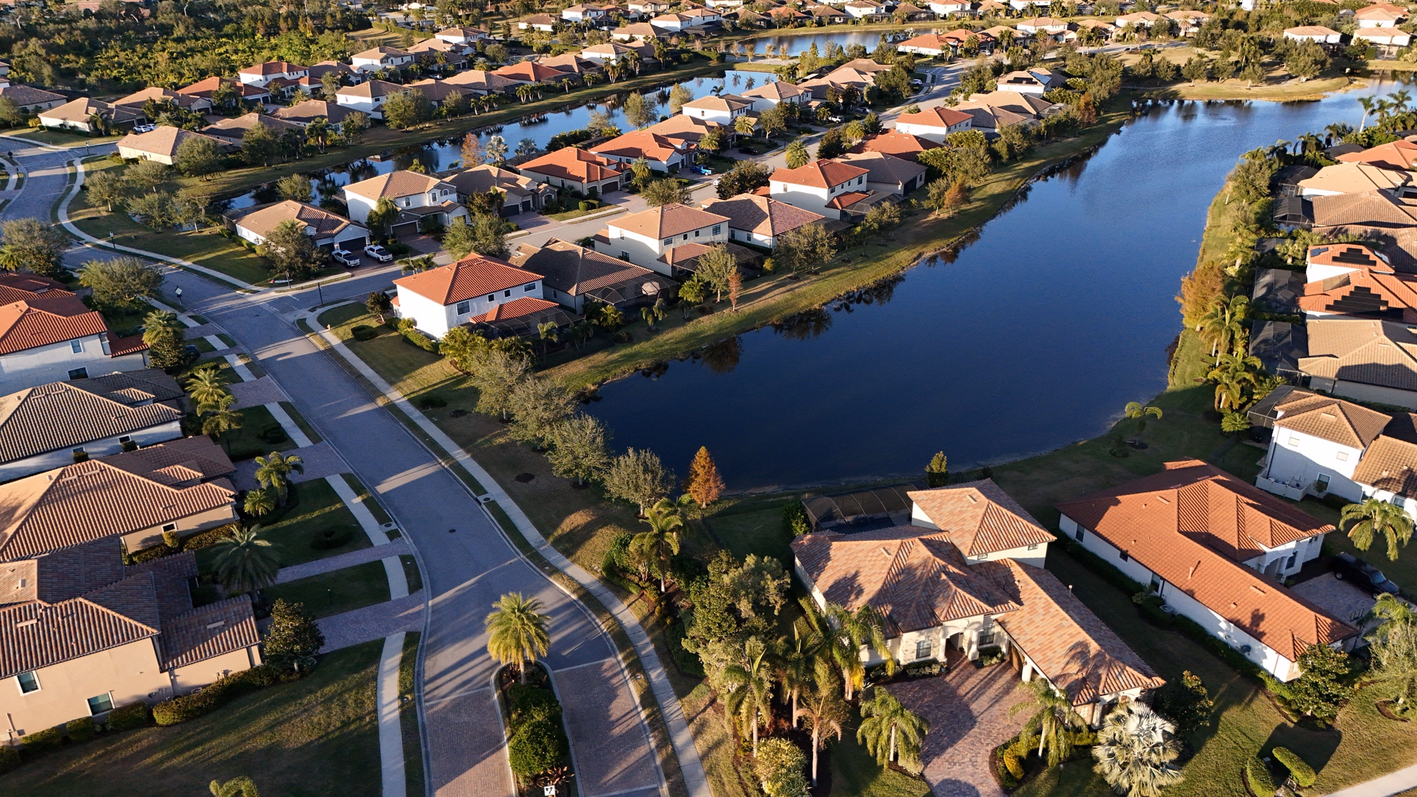 Aerial view of a suburban neighborhood in Lakewood Ranch, Florida, featuring waterfront homes, lush greenery, and winding streets.